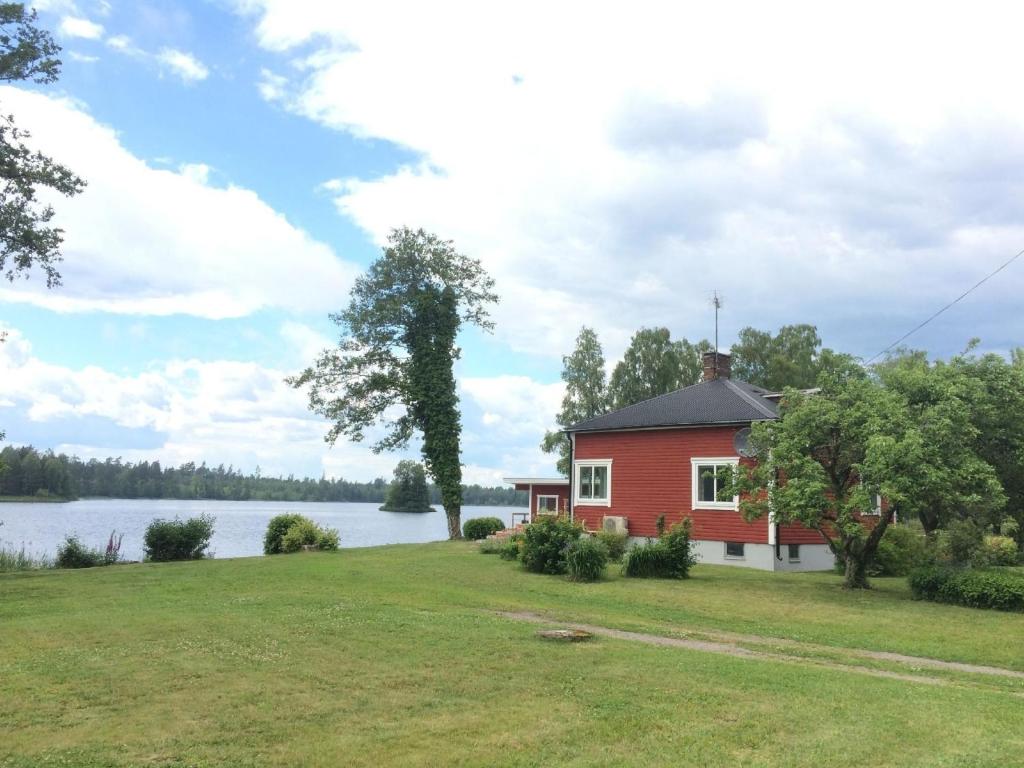 una casa roja a orillas de un lago en Ferienhaus mit Garten und Holzterrasse direkt am See 