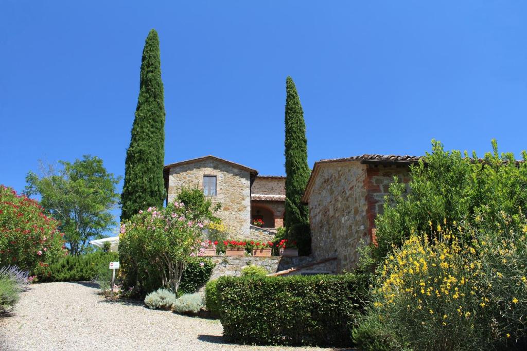 a stone house with two trees in a garden at Arco al Poggio - Arceno Rentals Club in San Gusmè