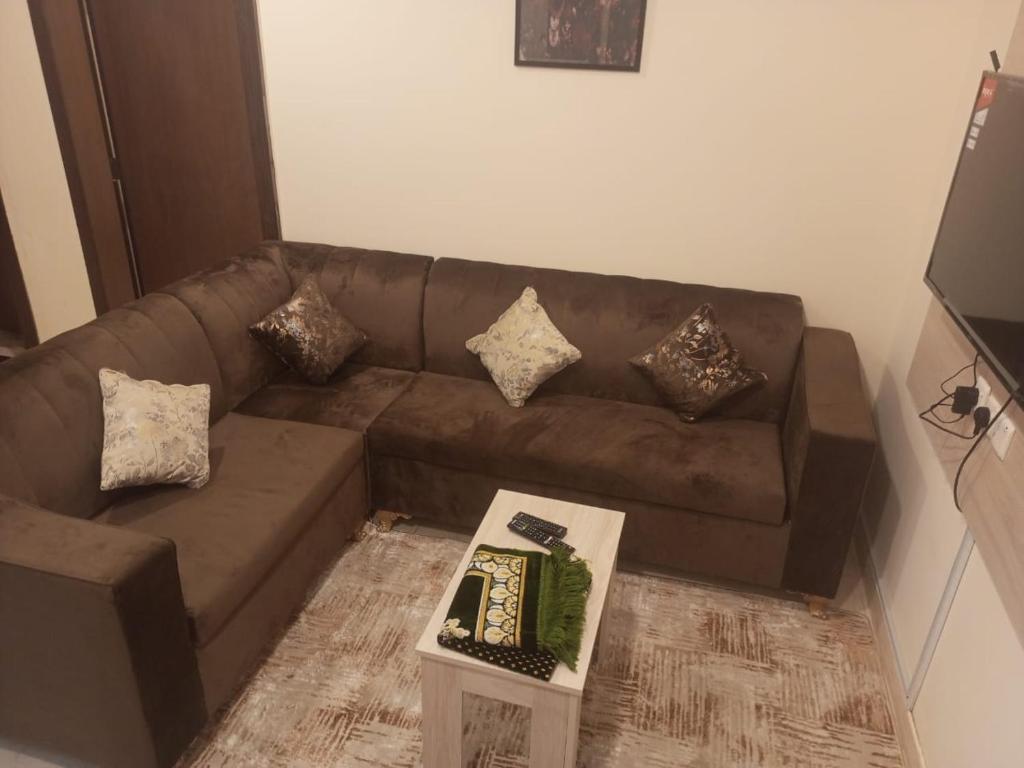 un divano marrone in un soggiorno con tavolo di VIP For Apartment - شقق فاخره a Al ‘Awālī