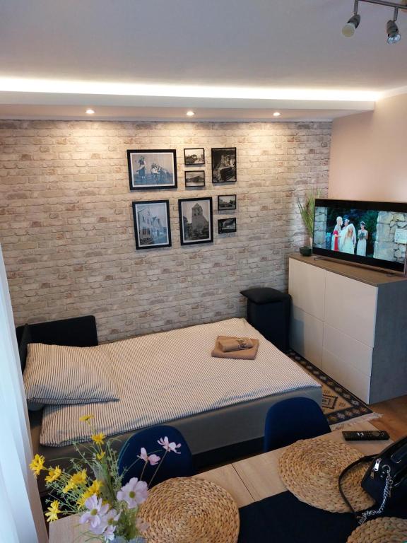a room with a bed and a tv on a brick wall at Apartament ZatokaPuck in Puck
