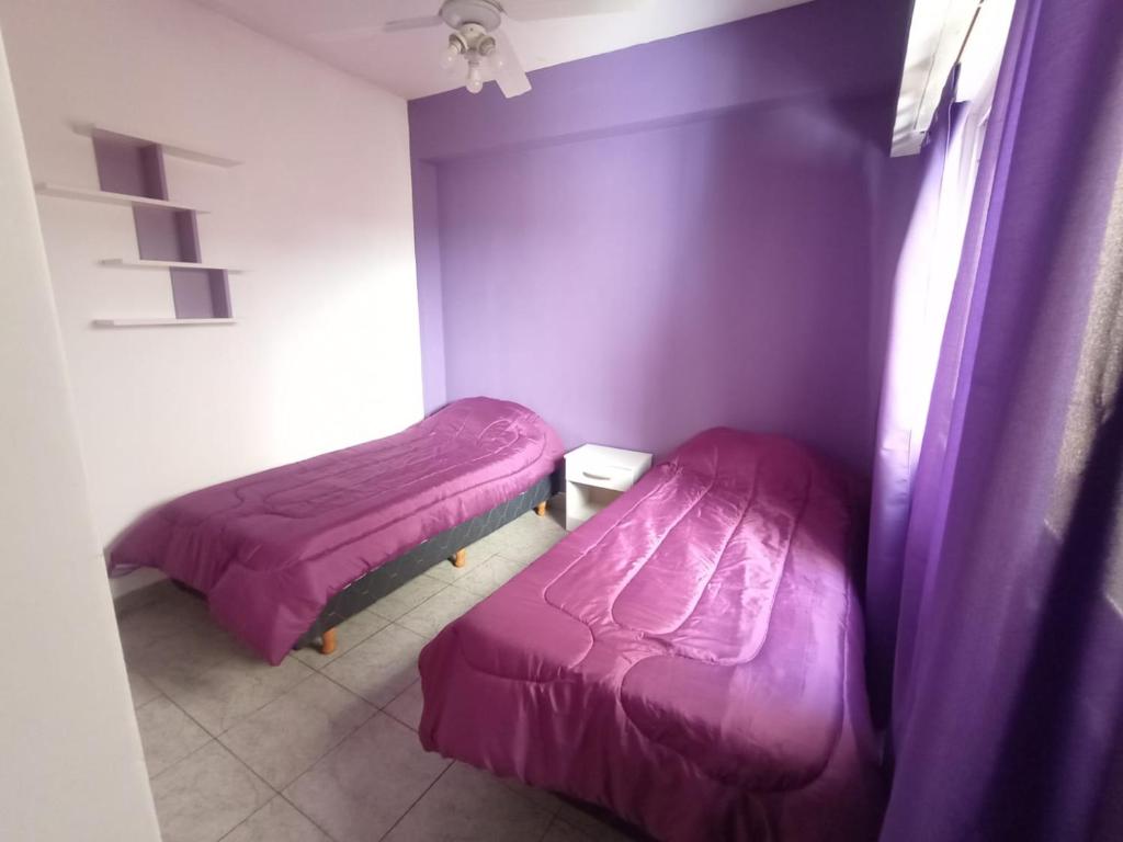 2 camas en una habitación con paredes moradas en Depto Caba Floresta en Buenos Aires