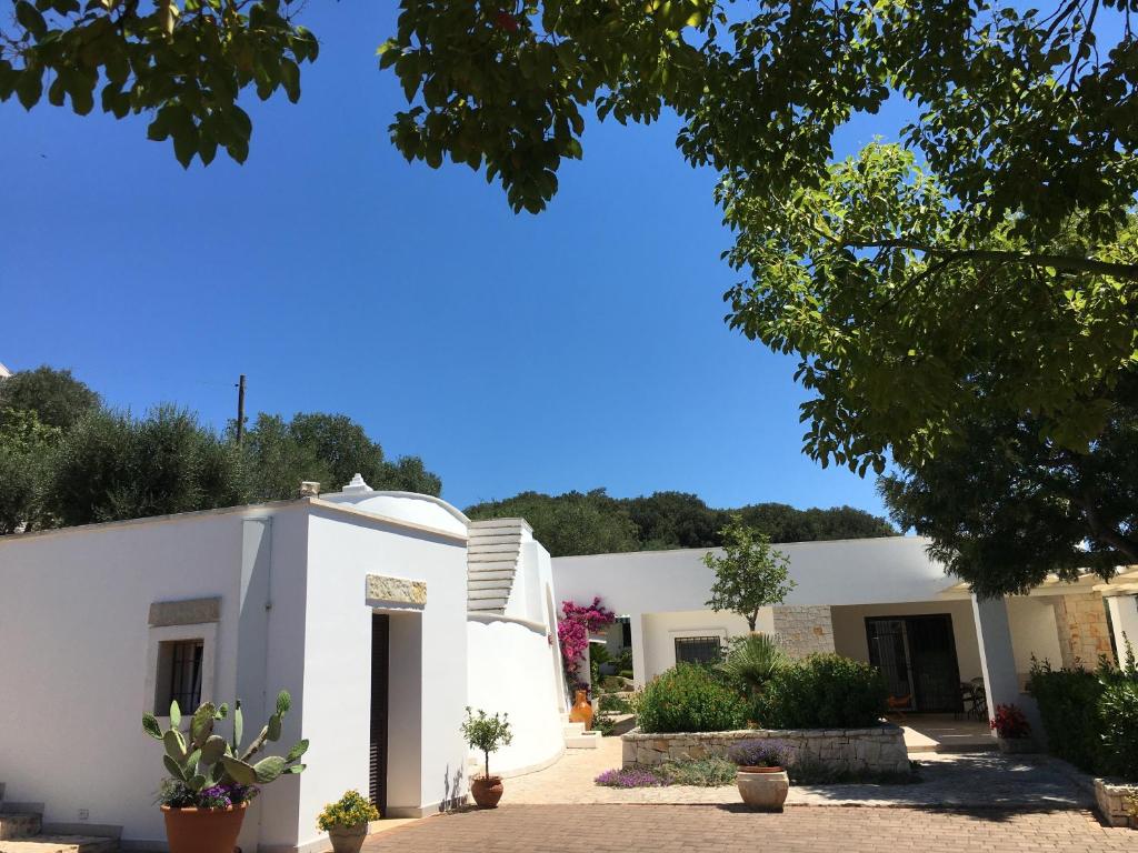a white house with trees in the foreground at IL Quieto Uliveto in Ostuni