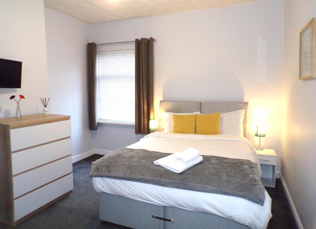 a bedroom with a large bed with yellow pillows at Lynam House in Stoke on Trent