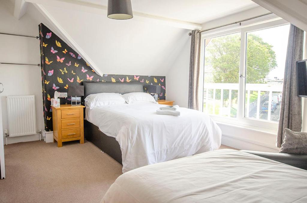 a bedroom with two beds and a window at Headlands - Room Only Accommodation in Falmouth