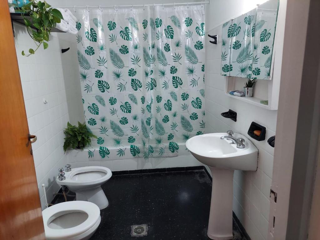 y baño con aseo, lavamanos y cortina de ducha. en Departamentos Avenida San Martin en Mendoza