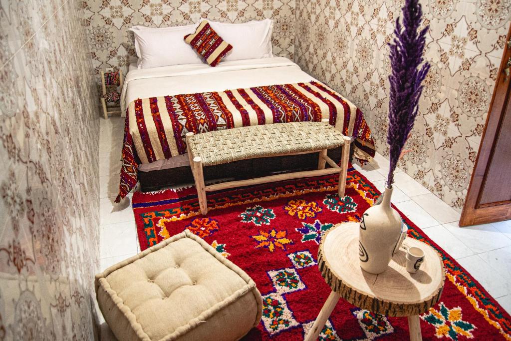Riad Fz Marrakech في مراكش: غرفة نوم بسرير وسجادة مع طاولة