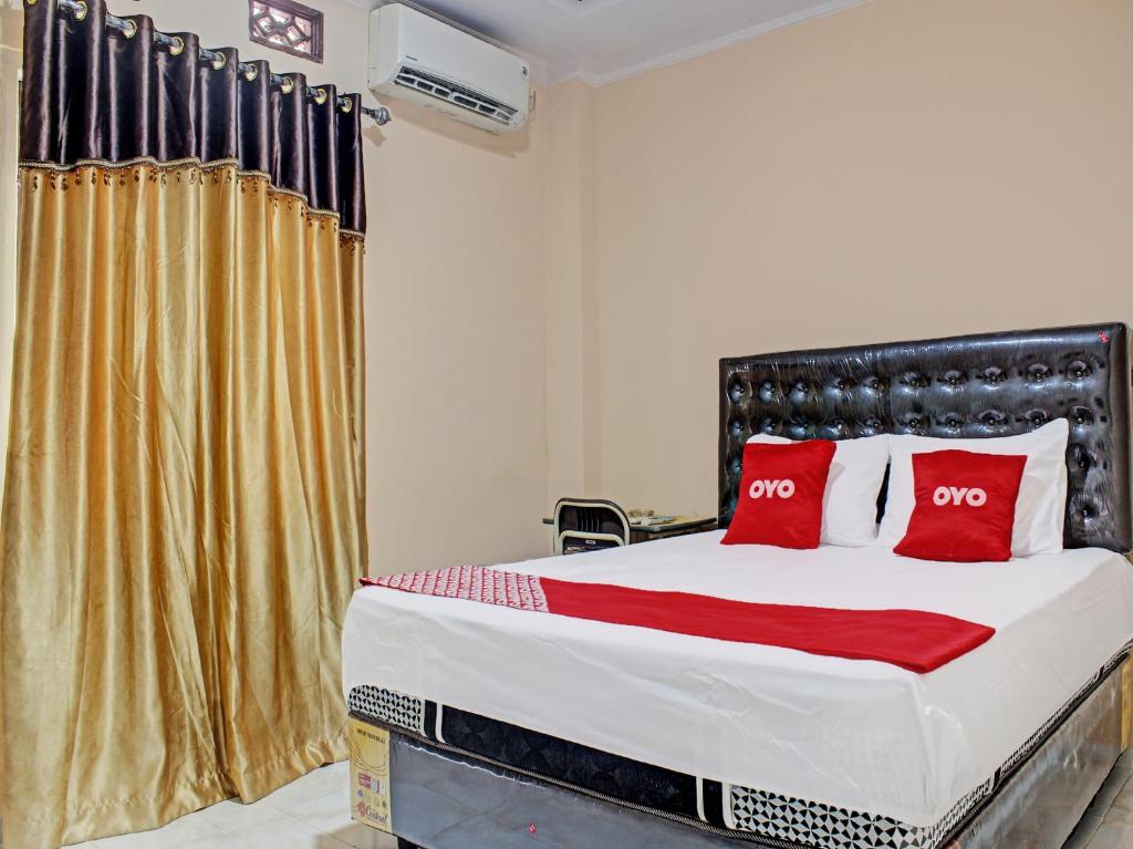 um quarto com uma cama grande e almofadas vermelhas em OYO 92193 Kos 21 em Kupang