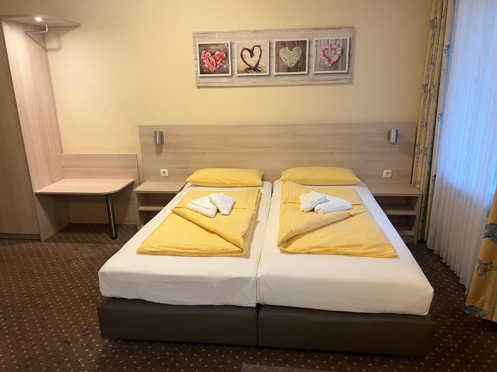 2 bedden in een hotelkamer met gele lakens en kussens bij M&M Hotel - Seevetal in Seevetal