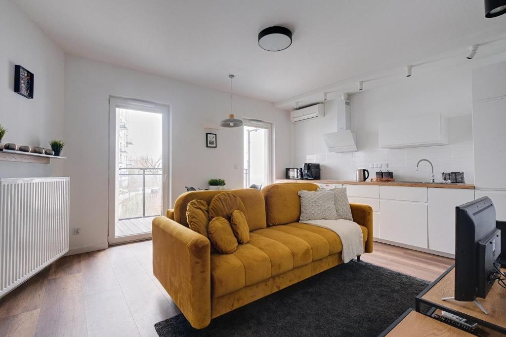 a living room with a yellow couch and a kitchen at Targowa 10 Modern 2BR Apt in Warsaw
