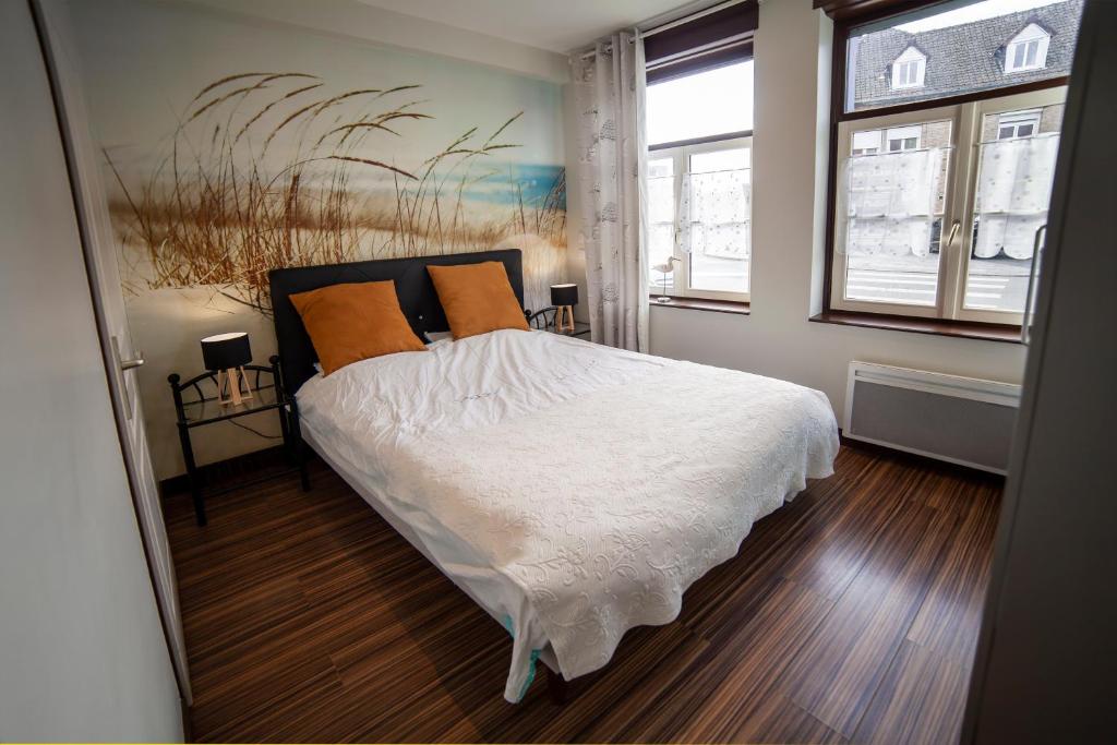 a bedroom with a bed with white sheets and orange pillows at Gite Bergues Centre in Bergues