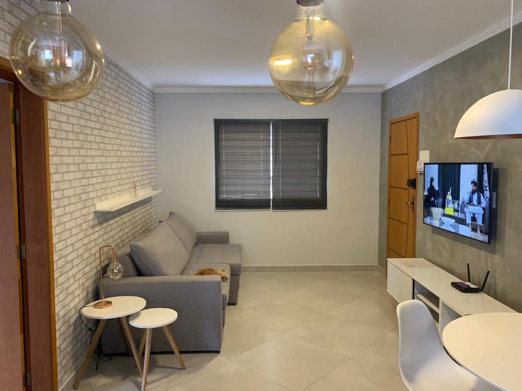 a living room with a couch and a tv at Apto 1o andar novo 2 Dorm - próximo ao centro in Poços de Caldas