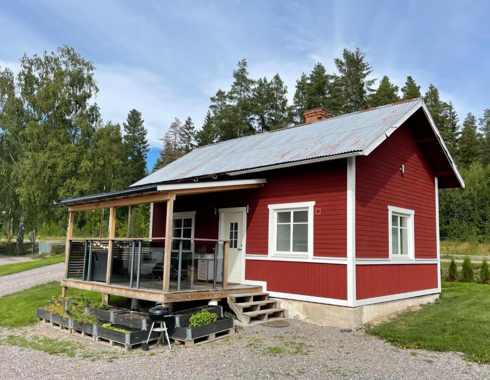 a red tiny house with a porch and a balcony at Backes Lillstuga in Borlänge