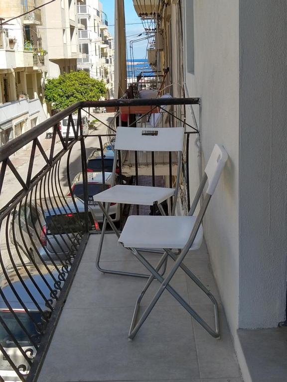 two chairs and a table on a balcony at Centrally Located Bugibba Apartment - Seaside Comfort in St Paul's Bay