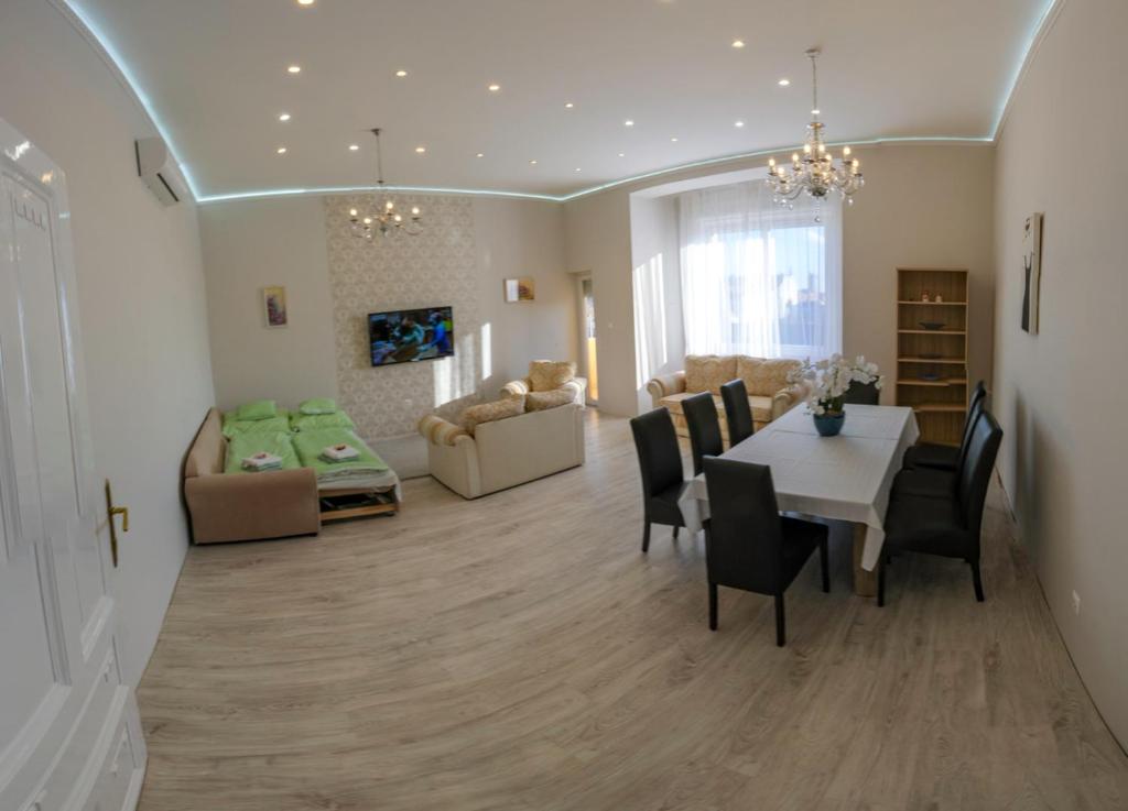 a dining room and living room with a table and chairs at Sky Apartment in Debrecen