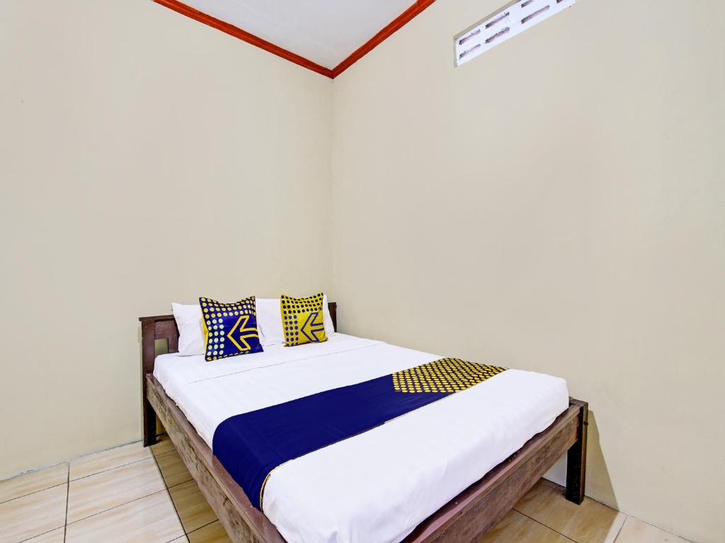 a bedroom with a bed with blue and yellow pillows at SPOT ON 92220 Sari Laut in Glagah