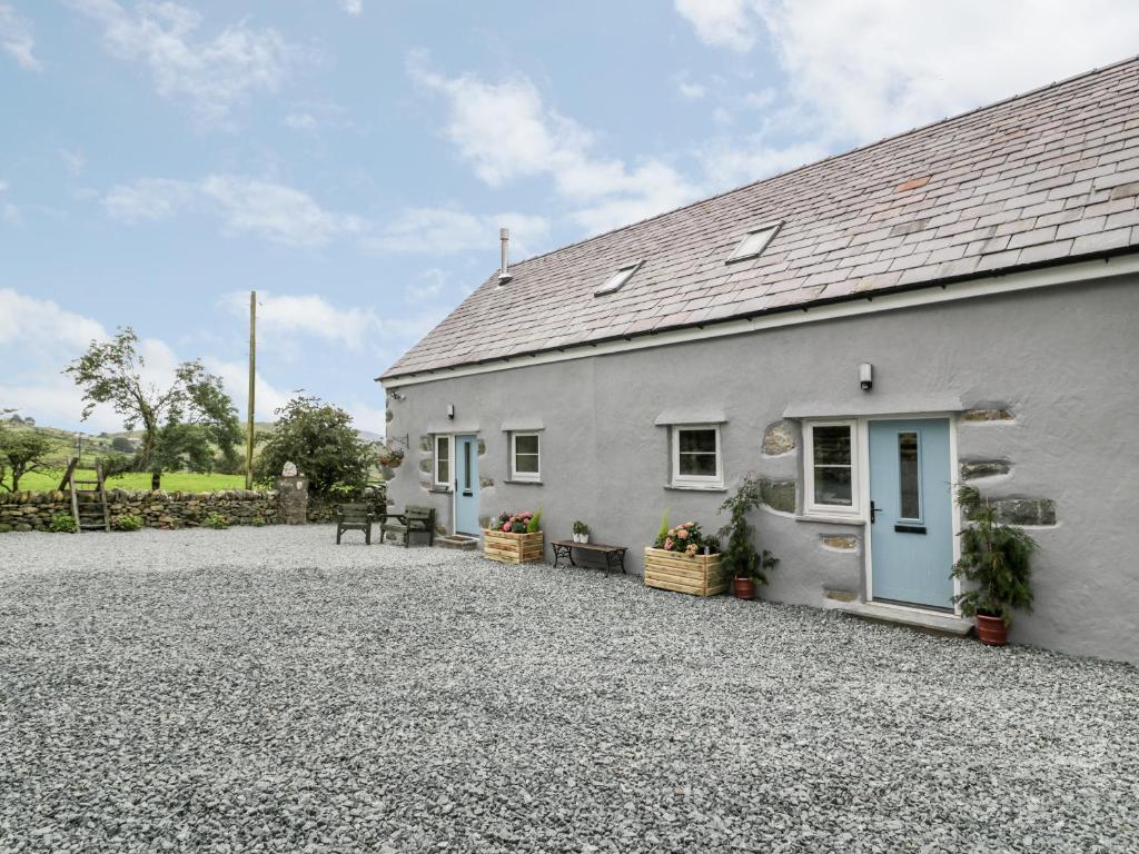 a white cottage with blue doors and a gravel driveway at Ffynnon Bach in Caernarfon