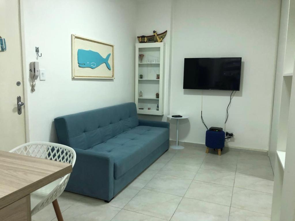 a living room with a blue couch and a flat screen tv at Apto em Santos com AR e Wi-Fi na rua da praia in Santos