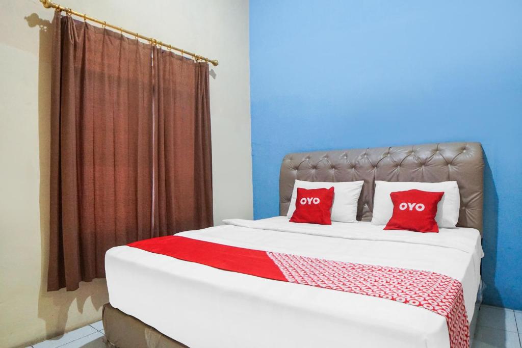 een slaapkamer met een bed met 2 rode kussens bij SUPER OYO 92076 Sky Residence Cengkeh in Medan