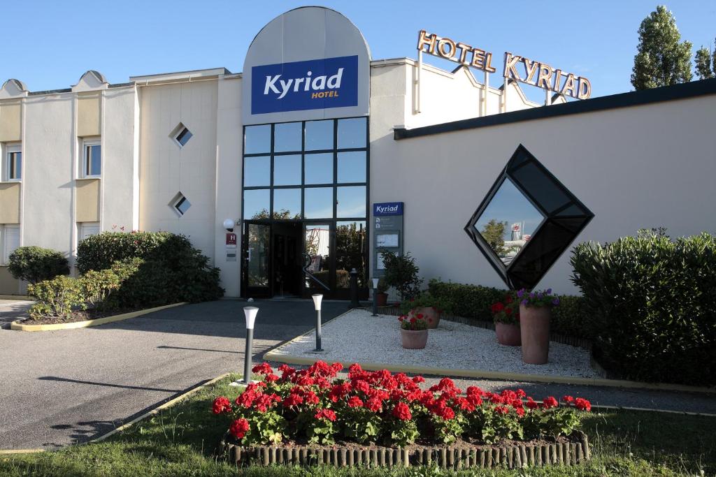 un hotel con fiori di fronte a un edificio di Kyriad Limoges Sud - Feytiat a Feytiat