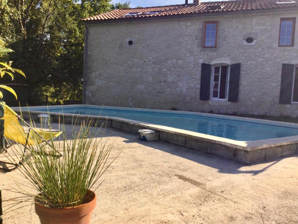 una piscina frente a un edificio con una casa en Belle et spacieuse chambre d’hôtes avec piscine, en Savignac-de-Duras
