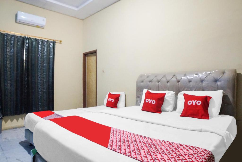 um quarto com uma cama grande e almofadas vermelhas em SUPER OYO 92075 Sky Residence Mawar em Sunggal