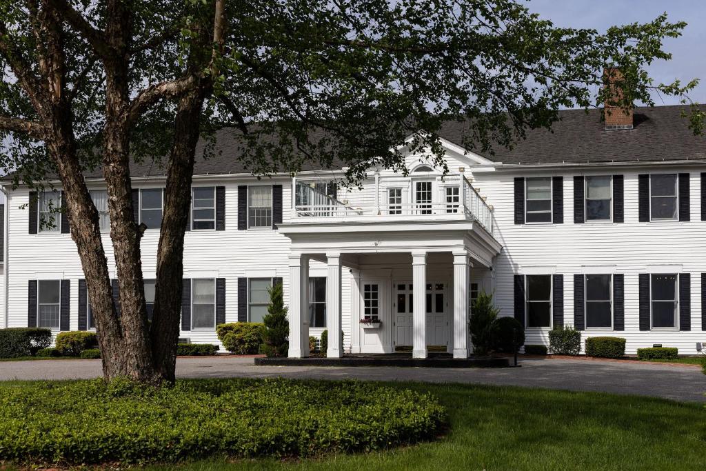 une maison blanche avec un arbre en face dans l'établissement The Litchfield Inn, à Litchfield