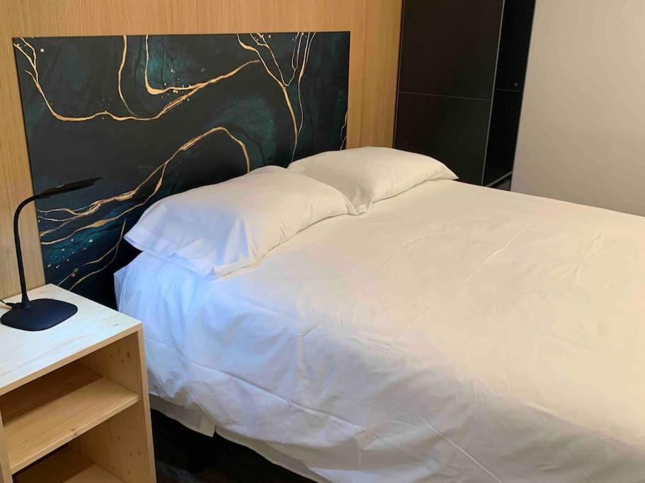 1 dormitorio con cama blanca y mesa con lámpara en L'Havana Xica, en Vilanova i la Geltrú