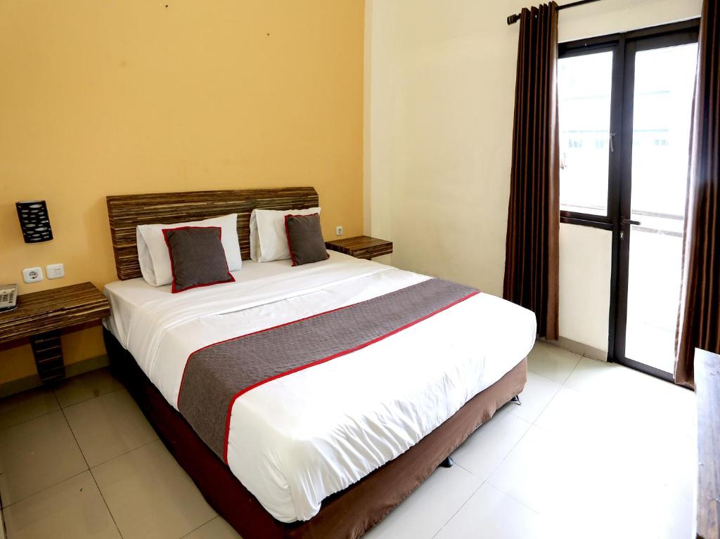 un grande letto in una stanza con una grande finestra di SUPER OYO Collection O 92130 Hotel Fiducia Kaji a Giacarta
