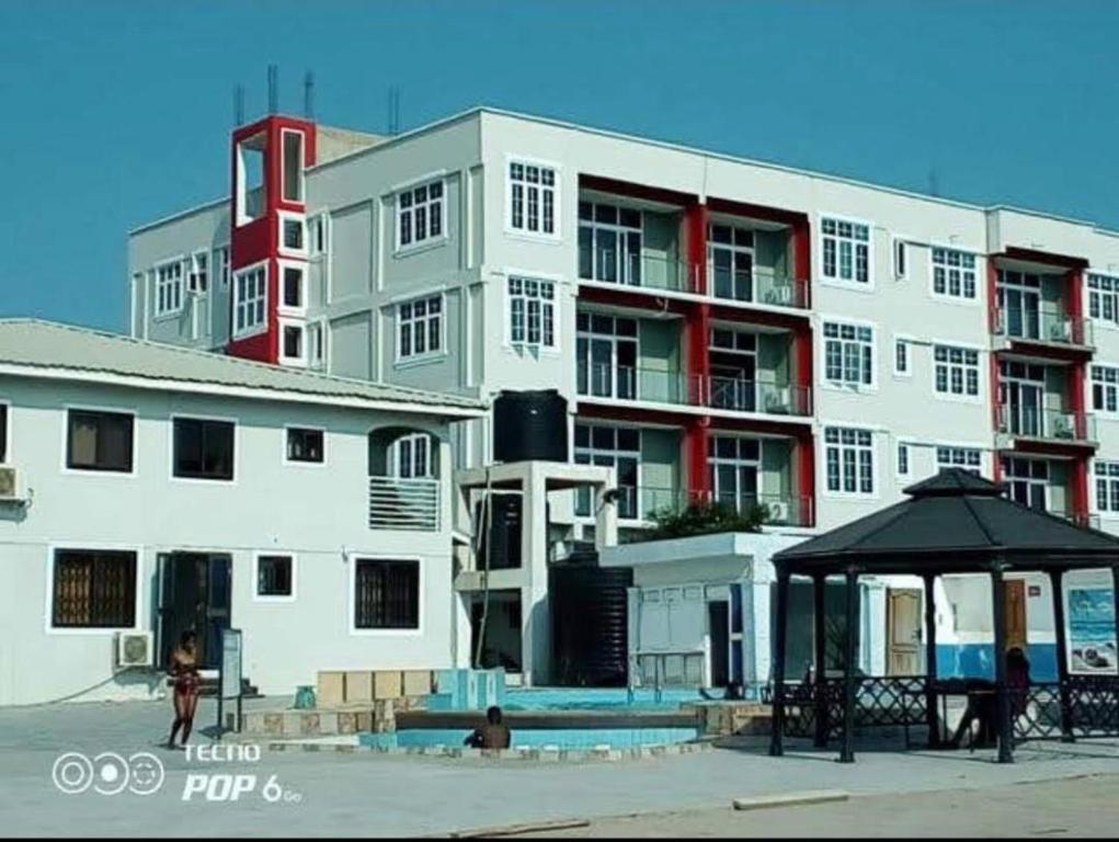 um grande edifício branco com um guarda-chuva em frente em Adonai Luxury Apartments Accra em Spintex