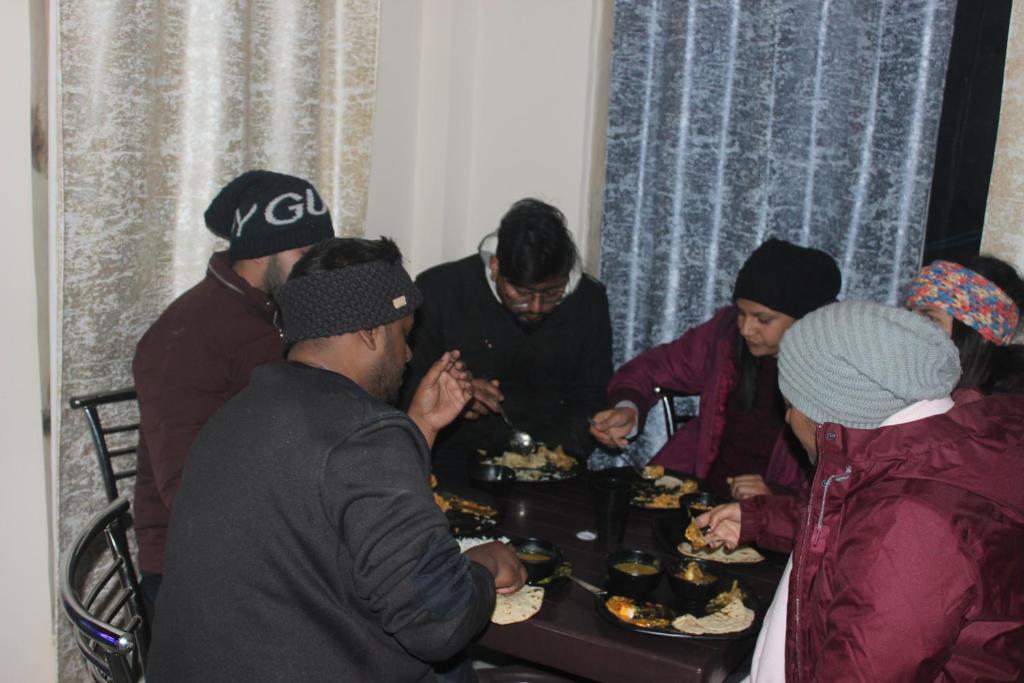 a group of people standing around a table eating food at Veda Inn in Chakrāta