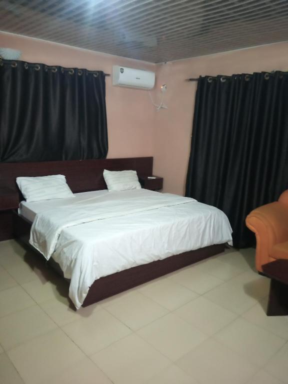 1 dormitorio con 1 cama grande y cortinas negras en Greendale apartment and Lodge, en Ibadán