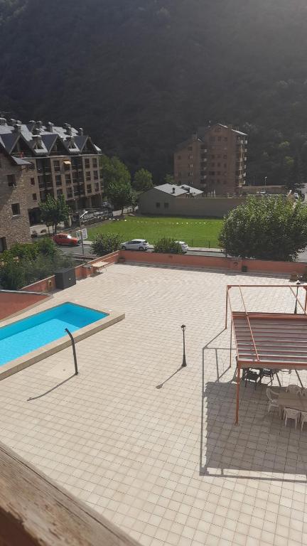 einen Pool mit einer Bank und einem Tisch in der Unterkunft Apartamento dúplex acogedor con piscina en Rialp in Rialp