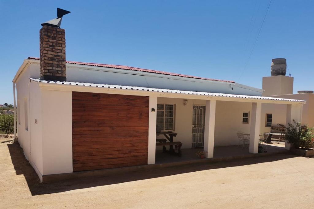 a white house with a wooden garage door at Hartland Gastehuis/Guesthouse in Vredendal