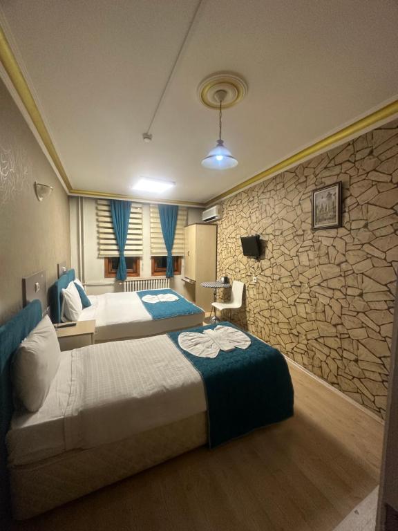 a bedroom with two beds and a stone wall at MEVLANA ŞEMS HOTEL in Konya