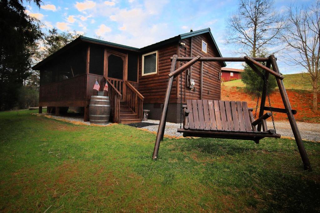 un columpio frente a una cabaña de madera en Smoky Hollow Outdoor Resort - Log Cabin, en Sevierville