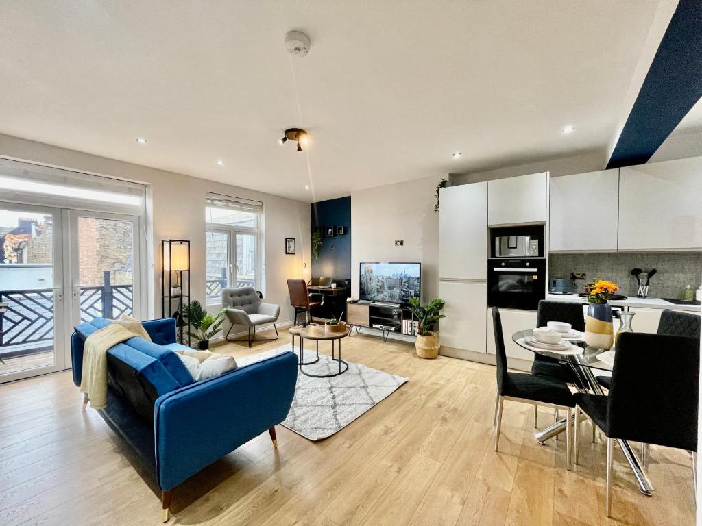 a living room with a blue couch and a kitchen at City Centre Gem in Southend near the beach, station and parking in Southend-on-Sea