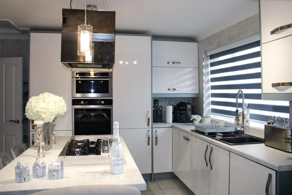 una cucina con armadi bianchi e piano cottura di Stylish 4-Bedroom House near NEC/BHX a Solihull