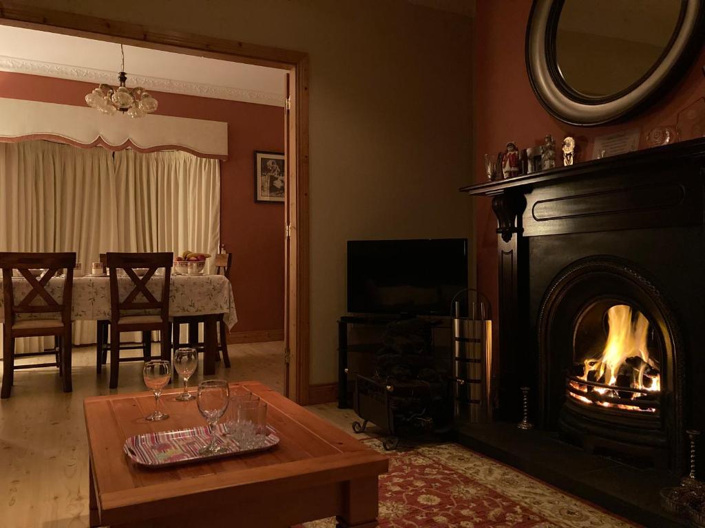 a living room with a fireplace and a table with wine glasses at Inny River Lodge in Rathowen