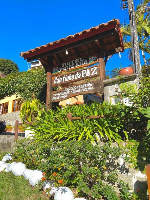a sign in a garden with plants and flowers at Pousada Cantinho da Paz in Itatiaia