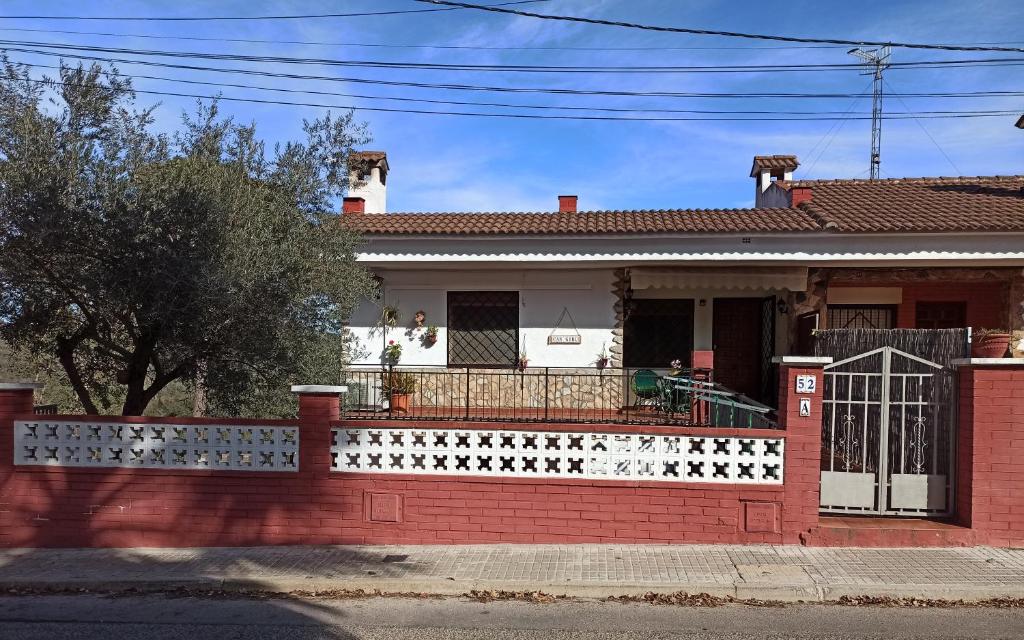 ein rotes Backsteinhaus mit einem weißen Zaun in der Unterkunft Apartamento Can Giru in Tordera