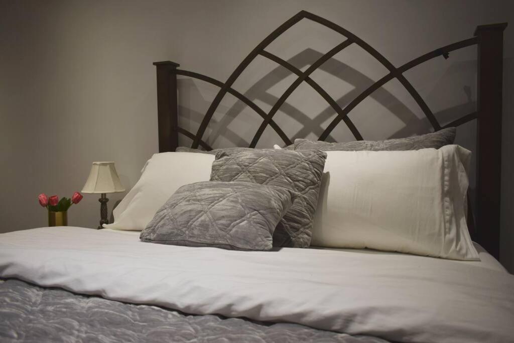 a bed with gray and white pillows on it at Home Away From Home - Basement Studio Apartment in Toronto