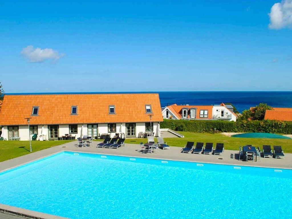 a house with a swimming pool next to the ocean at 5 person holiday home on a holiday park in Gudhjem in Gudhjem