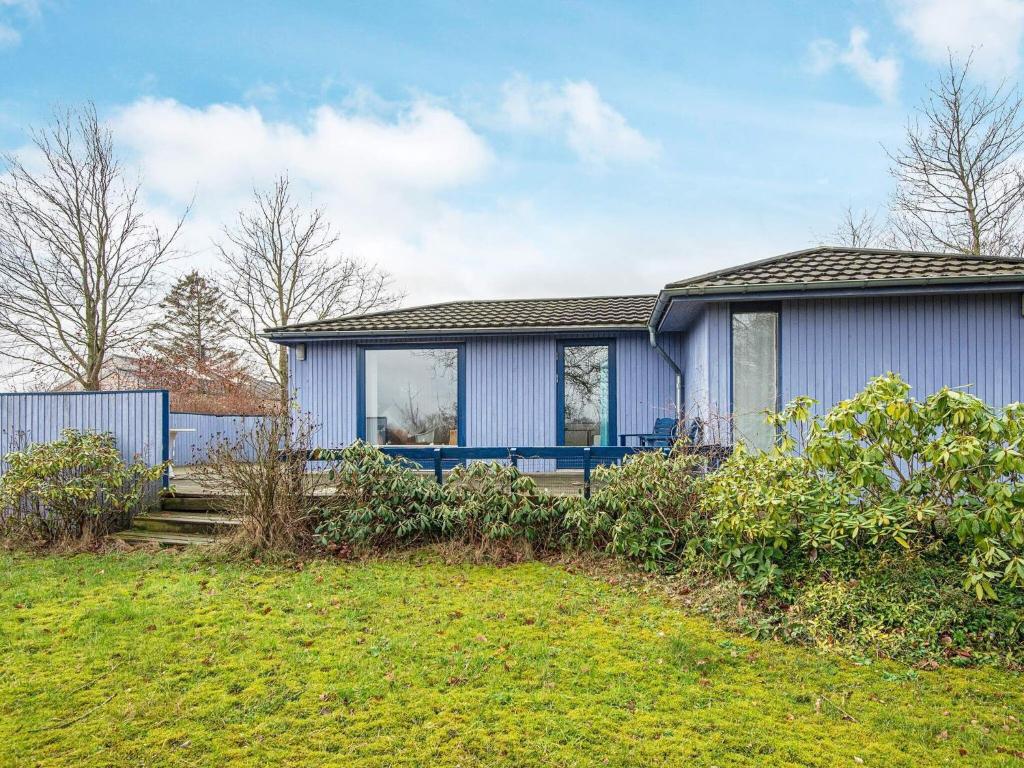 ein blaues Haus mit einem Rasenplatz davor in der Unterkunft 4 person holiday home in Kolding in Kolding