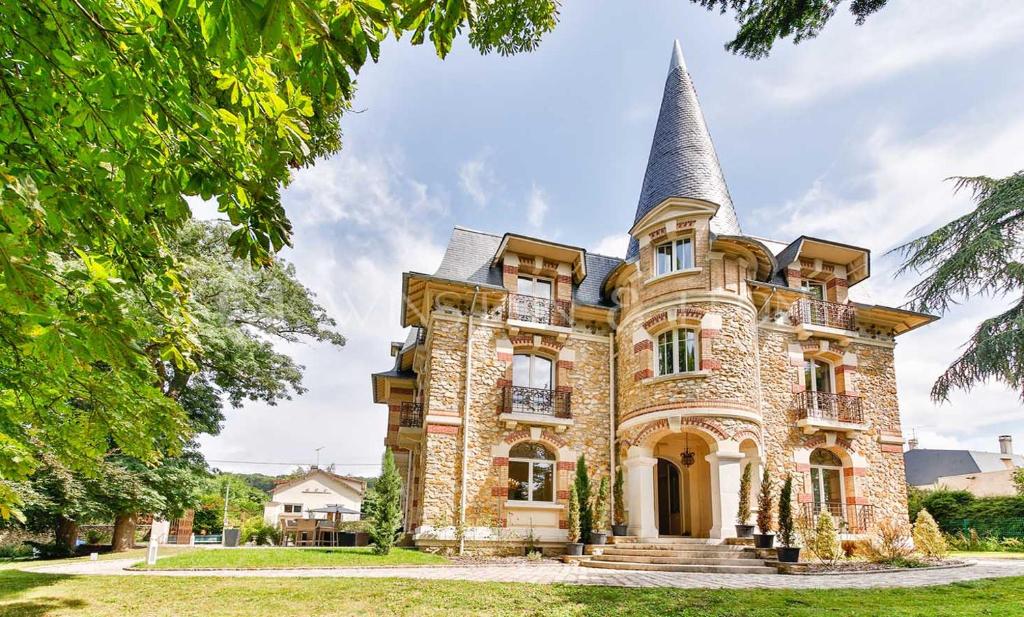 ein altes Steinhaus mit Turm oben in der Unterkunft Château De La Feuilleraie Maison de Maître in Saint-Leu-la-Forêt