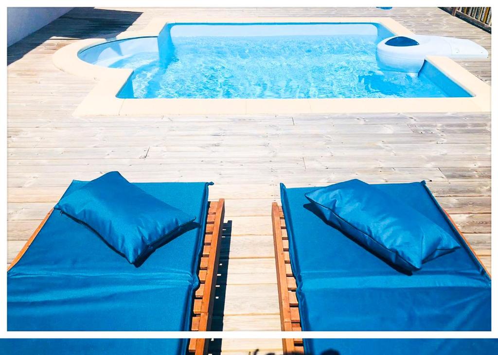 a pool with two blue cushioned beds next to a swimming pool at Villa GAIA in Les Trois-Îlets
