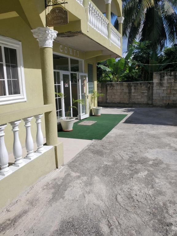 Edificio amarillo con porche y balcón en Comfy Guest Rooms en Port Antonio
