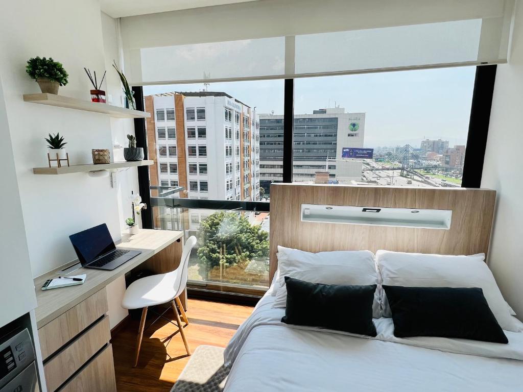 Schlafzimmer mit einem Bett, einem Schreibtisch und einem Fenster in der Unterkunft Apartaestudio en el Chico in Bogotá