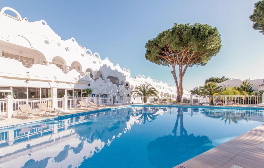 uma piscina num resort com cadeiras e uma palmeira em Stunning Home In Las Chapas Marbella With Kitchenette em Marbella