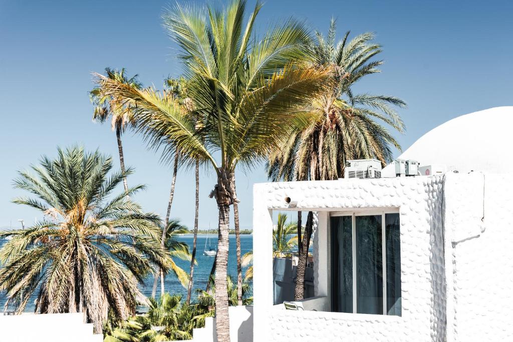 a white building with palm trees in front of the ocean at Hotel Allende in La Paz