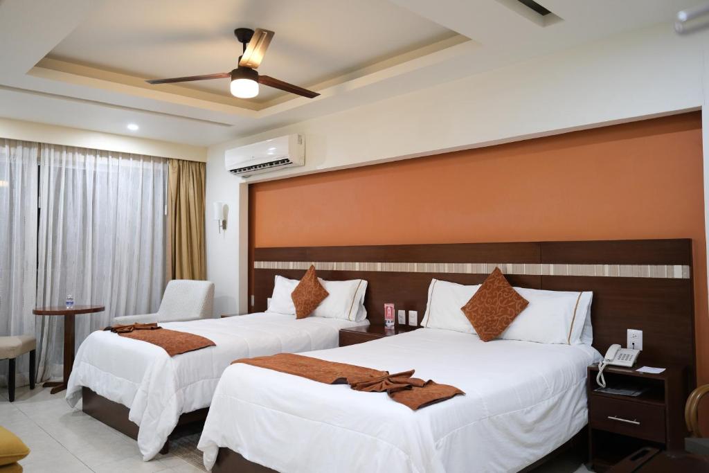 2 camas en una habitación de hotel con sábanas blancas en Ivissa Hotel en Santiago Pinotepa Nacional